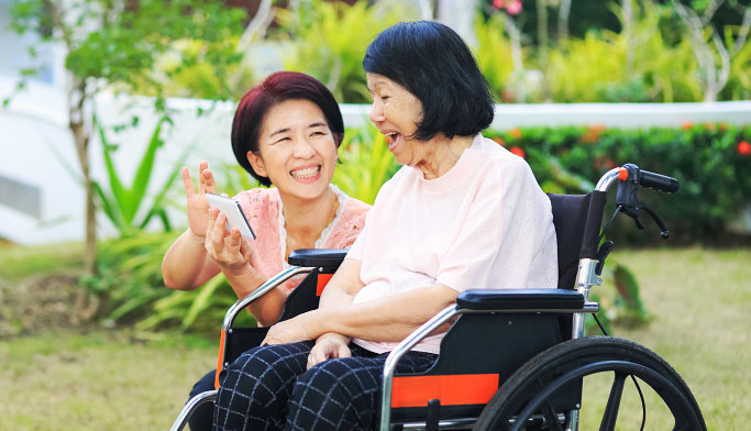happy senior woman on wheelchair with her caregiver